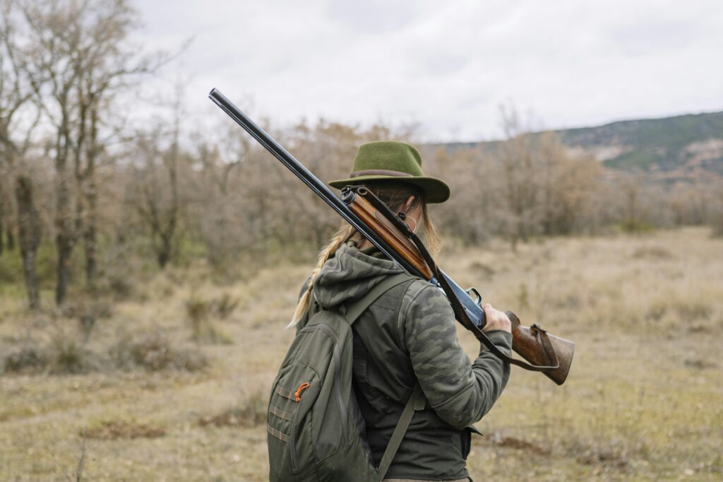Hunter woman with shotgun hunting in the field.